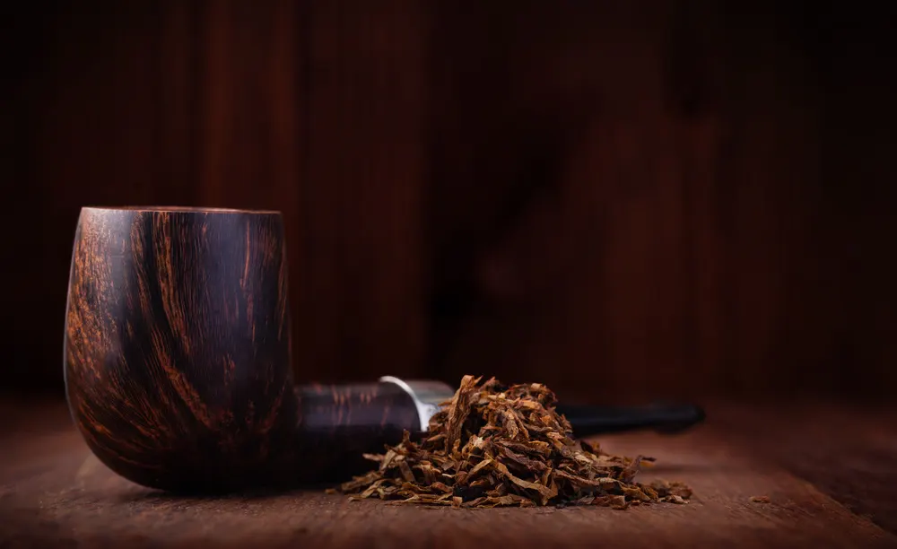 Briarová fajka a kôpka tabaku na drevenom pozadí