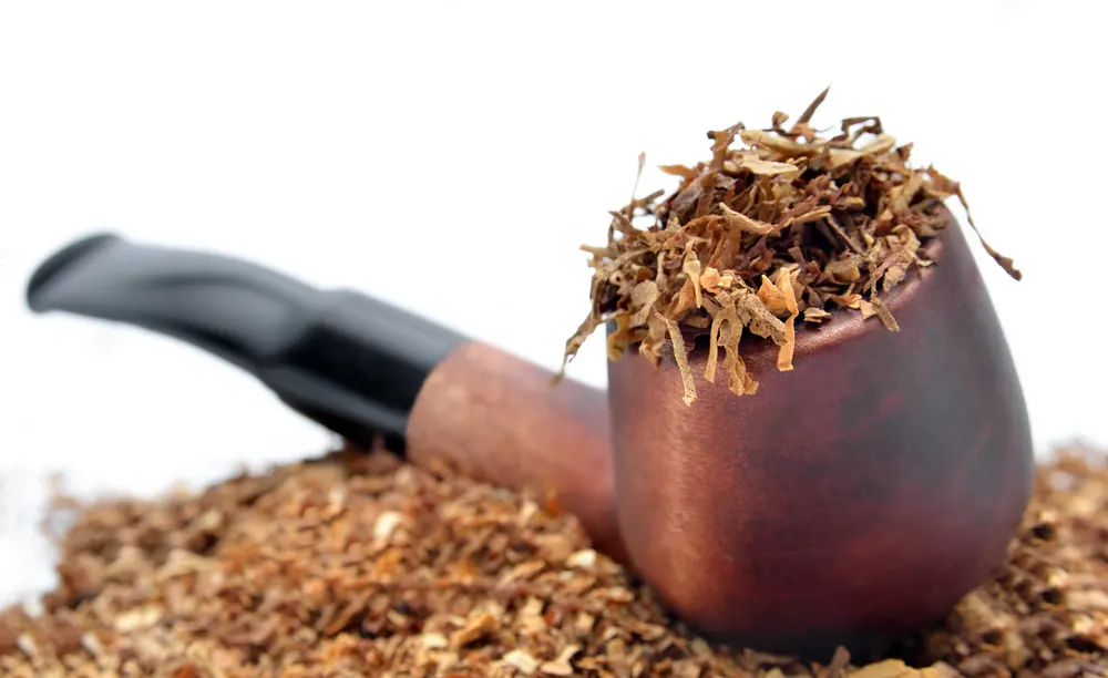 Fajkový tabak a briarová fajka na tabak - fajkový tabak napchatý do hlavičky fajky